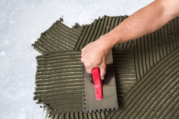 Worker hand with trowel working or tile work | arab maintenance